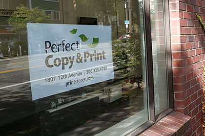 Picture of our sign and name in our shop window, surrounded by red brick